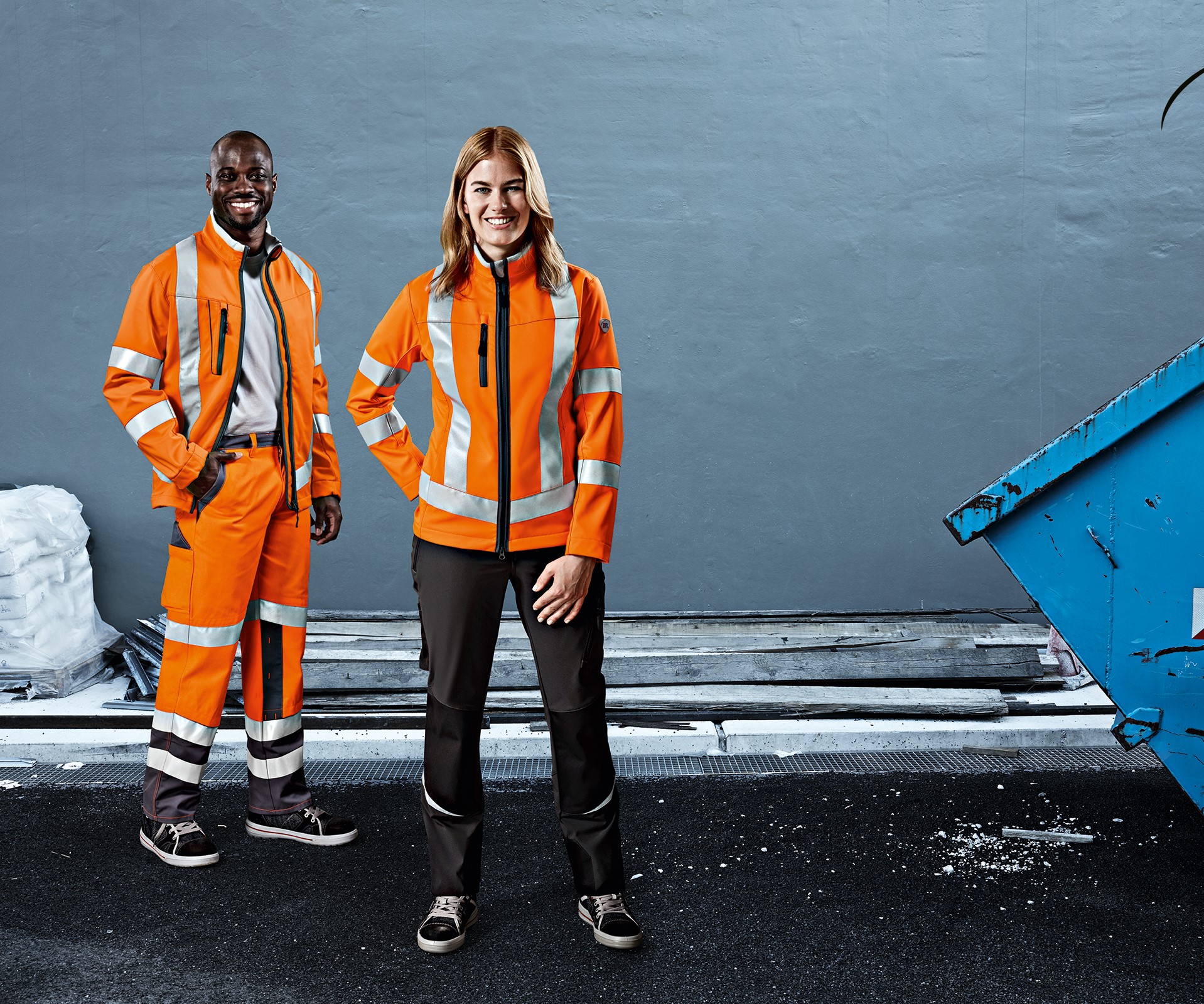 A woman and a man in high-visibility protective clothing stand next to a container.